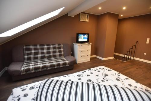 a bedroom with a bed and a couch and a television at Center Apartment Čakovec in Čakovec