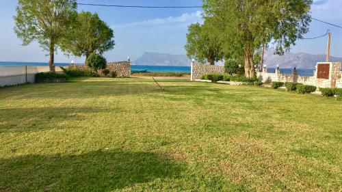 a yard with trees and the ocean in the background at Vasso Apartments 3 in Kissamos