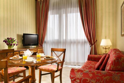 a living room with a table and a couch at UNA Hotels Hotel & Residence Contessa Jolanda Milano in Milan