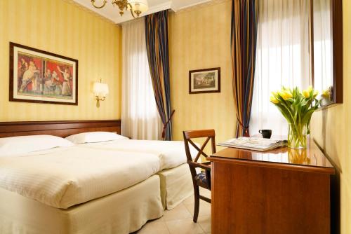 a hotel room with two beds and a desk at UNA Hotels Hotel & Residence Contessa Jolanda Milano in Milan