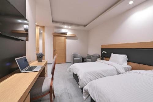 a hotel room with two beds and a laptop on a desk at The Residence 649 in An Naqqāsh