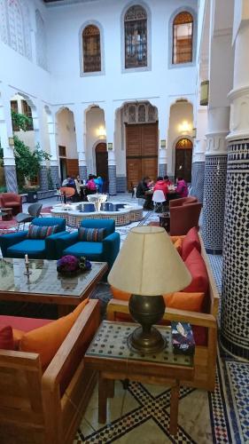 un grand hall avec des canapés, des tables et une lampe dans l'établissement Riad jasmins & Spa, à Fès