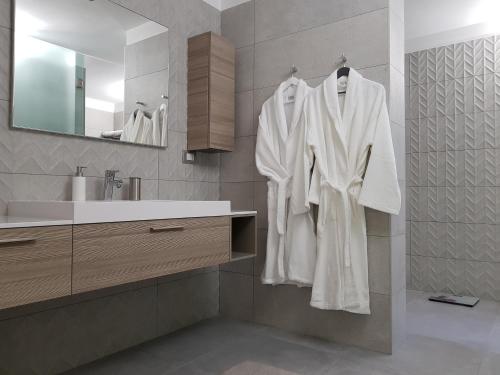 a bathroom with white robes hanging on a wall at Luxury Apartments Beauty Gardens in Sirmione