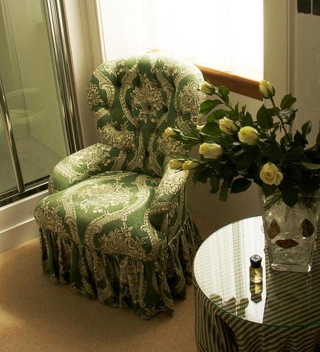 a green chair and a table with a vase of flowers at Glenburnie House in Oban