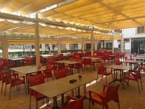 アルカラ・デル・フカルにあるHostal Rural Ramblaのテーブルと赤い椅子が備わる空きレストランです。