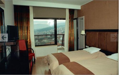 a hotel room with two beds and a large window at Hotel Makedonia in Veria
