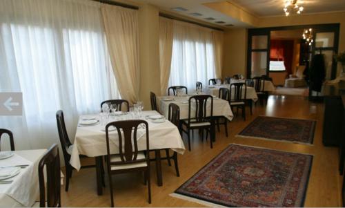 a dining room with white tables and chairs and windows at Hotel Makedonia in Veria