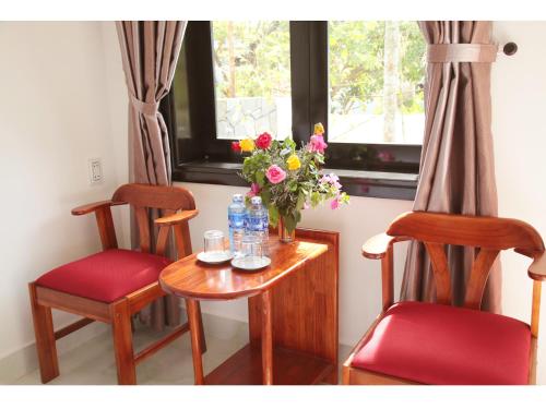 Sunny Garden Homestay في هوي ان: طاولة مع كرسيين و مزهرية من الزهور
