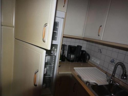 Eine Küche mit weißen Schränken, Spüle und Herd in der Unterkunft Ferienwohnung Wattkieker in Husum