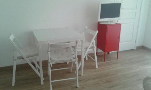 ニースにあるBlanchetteの白いテーブルと椅子(赤いキャビネットのコンピュータモニター付)