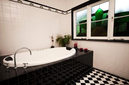 uma banheira na casa de banho com piso preto e branco em Mountain Whispers The Gatsby em Katoomba