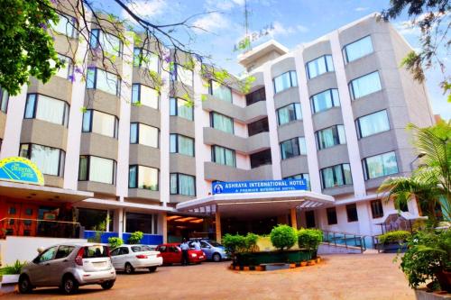 a large building with cars parked in front of it at Ashraya International Hotel in Bengaluru
