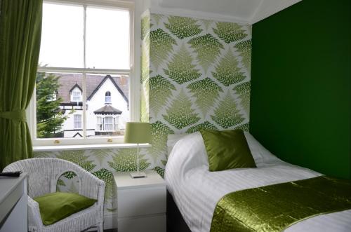 a green bedroom with a bed and a window at Audley Guest House in Llandudno