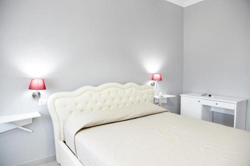 a white bed in a white bedroom with two lamps at Hotel Ospite Inatteso in Montalto di Castro