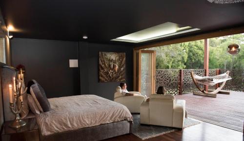 a bedroom with a bed and a balcony with a hammock at Mudstone Spa Retreat in Pemberton