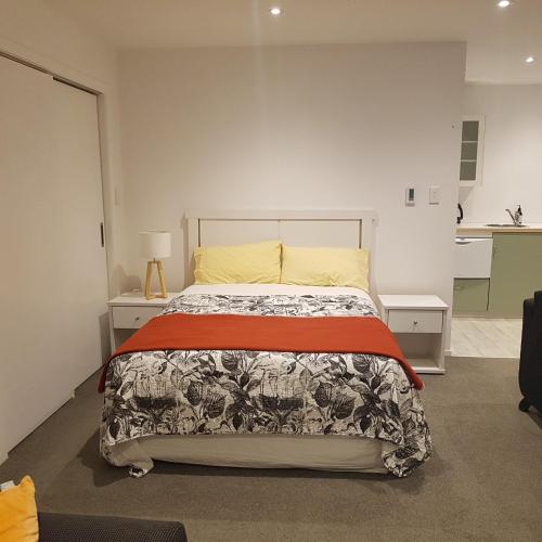 1 dormitorio con cama y pared blanca en Near the shore en Waikanae