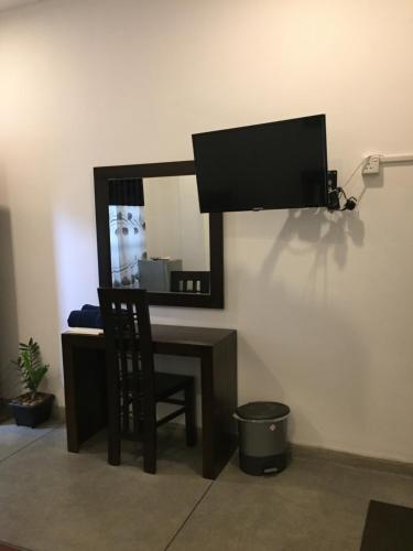 a desk with a television and a chair in front of a mirror at US Motel Colombo in Homagama