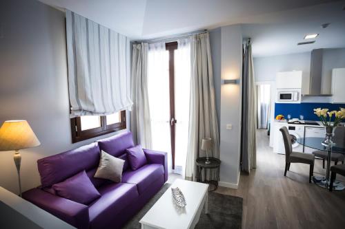 a living room with a purple couch and a kitchen at La Casa de la Trinidad Suites in Granada