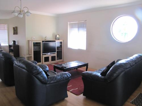 a living room with two black leather couches and a television at Ocean View Retreat in Jurien Bay