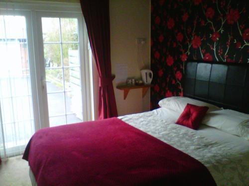 a bedroom with a bed with a red pillow on it at Prince Charlie's Cottage in Gretna Green