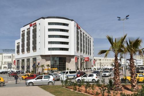 a parking lot with cars parked in front of a building at Ibis Sfax in Sfax