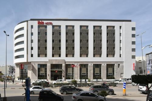 a large white building with cars parked in a parking lot at Ibis Sfax in Sfax