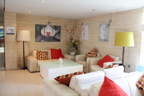 a living room with white couches and red pillows at Palmera Beach in Pilar de la Horadada