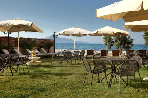 a group of tables and chairs with umbrellas and the ocean at Almyrida Resort in Almirida
