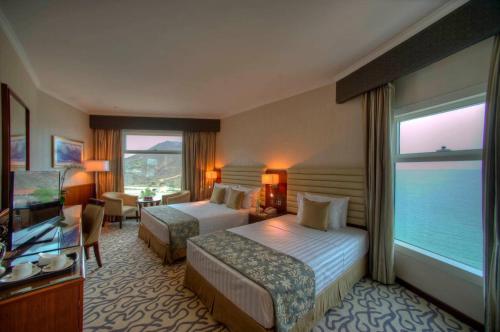 a hotel room with two beds and a large window at Oceanic Khorfakkan Resort & Spa in Khor Fakkan