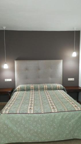 a bed in a bedroom with two lights above it at Puerta del Arco in Riópar
