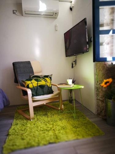 a room with a chair and a table and a tv at cres art studio lime apartment in Cres