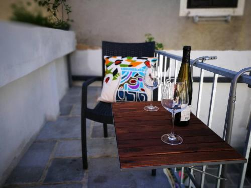 a wooden table with a bottle and a wine glass at cres art studio lime apartment in Cres