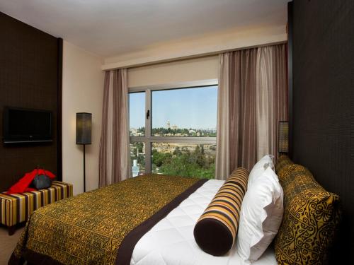 a bedroom with a bed and a large window at Dan Boutique Hotel Jerusalem in Jerusalem