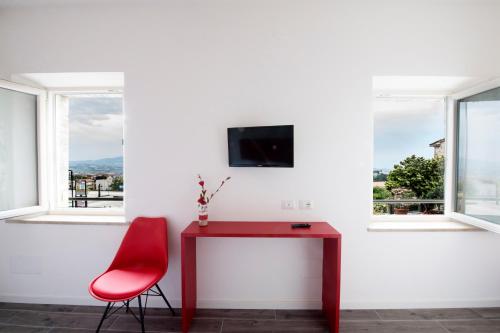 uma secretária vermelha e uma cadeira vermelha num quarto com janelas em CalaLaNotte em Recanati