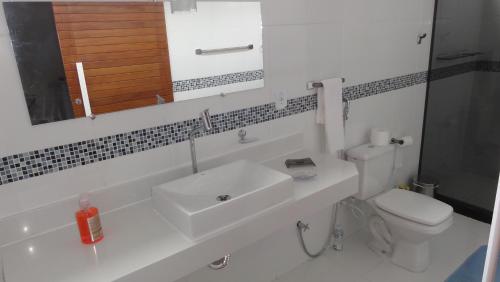 W łazience znajduje się umywalka, toaleta i lustro. w obiekcie Linda Suíte perto da Praia do Forno w mieście Arraial do Cabo
