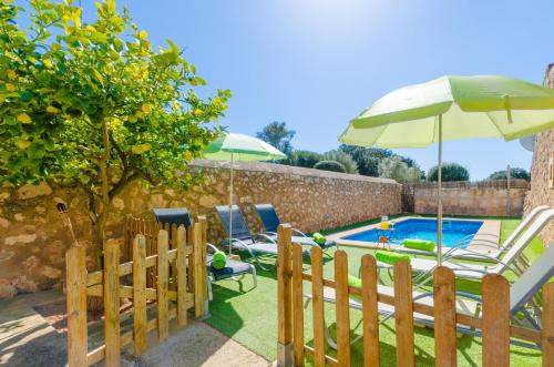 a fence with chairs and an umbrella next to a pool at Finca Can Maria Costitx in Costitx