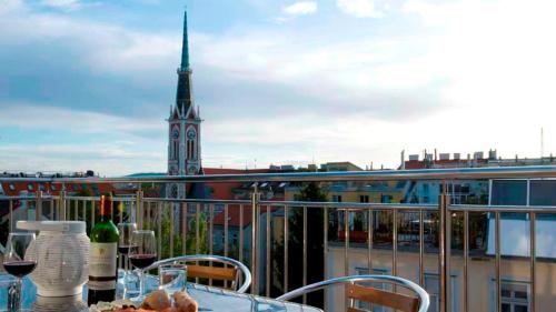 a table with wine glasses on a balcony with a clock tower at RAFAEL KAISER - Premium Apartments - Contactless Check-In in Vienna