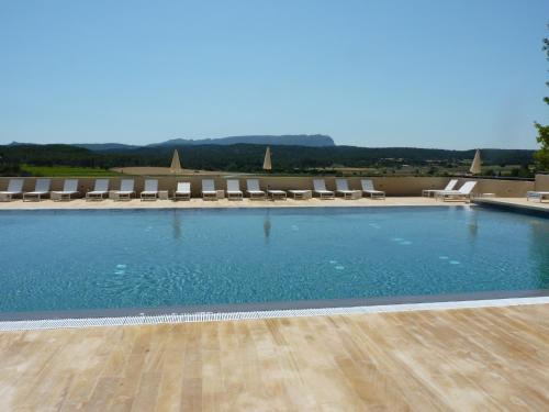 une grande piscine avec des chaises longues dans l'établissement La Bastide de Venelles, à Venelles