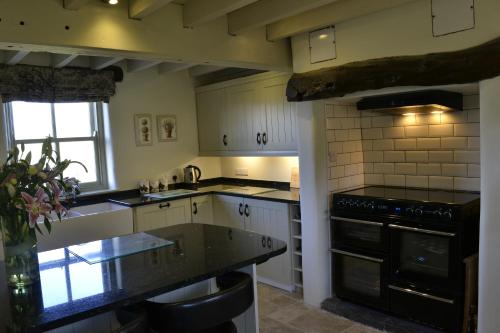 a kitchen with white cabinets and black appliances at Birkend Farmhouse in Feetham
