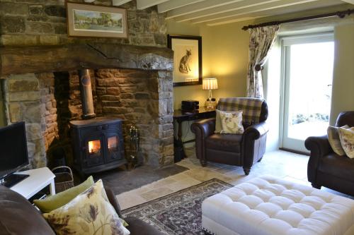 a living room with a stone fireplace and a couch at Birkend Farmhouse in Feetham