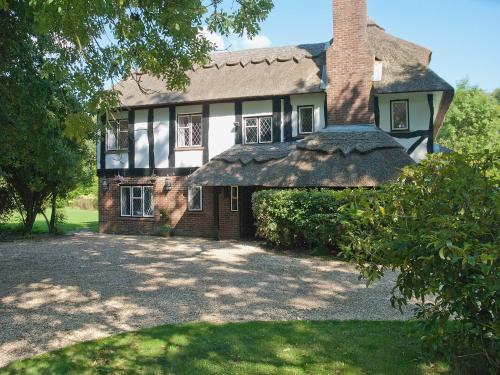 a large brick house with a thatched roof at Silverland in Hordle