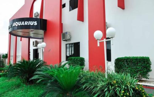 a red and white building with plants in front of it at Aquarius Hotel Aquarius in Ariquemes
