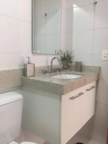 a white bathroom with a sink and a mirror at Apartament Piratininga in Niterói