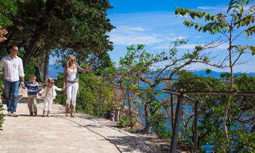 a family walking down a path near the ocean at Hotel Kristal - Liburnia in Opatija