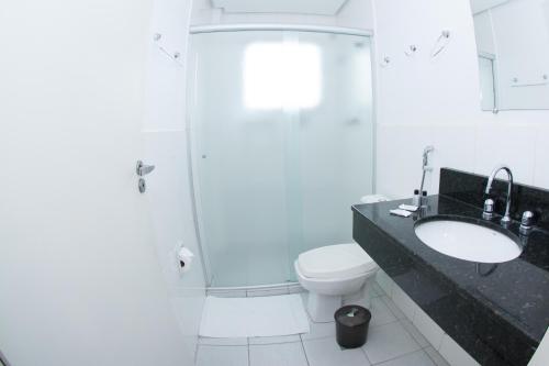 a bathroom with a toilet and a sink and a shower at Plaza Dutra Hotel in Caçapava