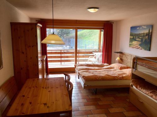 1 Schlafzimmer mit 2 Betten, einem Tisch und einem Fenster in der Unterkunft Résidence Castel Club Leysin Parc in Leysin