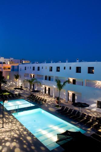 a large building with a swimming pool at night at Migjorn Ibiza Suites & Spa in Playa d'en Bossa