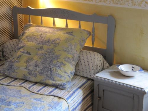 a bed with a pillow and a bowl on a night stand at Le Mas des Clots in Upie