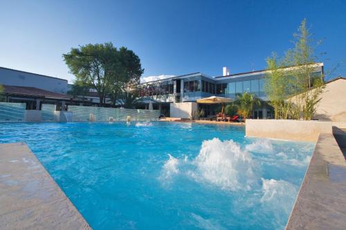 a swimming pool with blue water in front of a building at Hotel Coral Plava Laguna in Umag