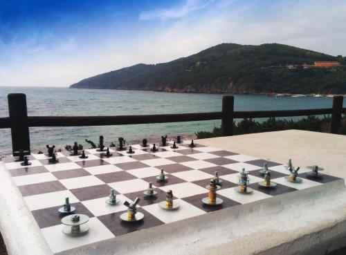 a chess board on a table next to the ocean at Hotel Capo Sud in Lacona